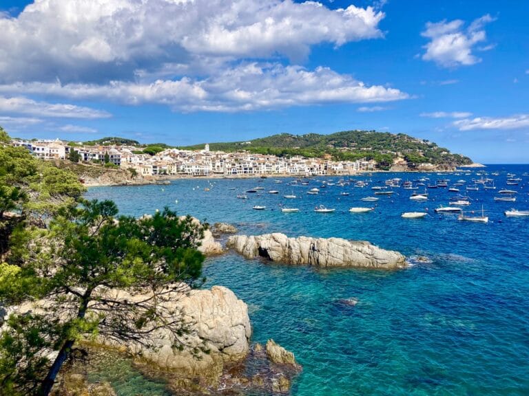 Vue panoramique sur Cadaqués en Espagne avec la Méditerranée aux teintes émeraude et roches typiques au premier plan, lors d’un séjour en Costa Brava